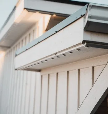 Aluminum LED track screwed under the roof edge — the mechanical fastening that survives freeze-thaw where tape fails